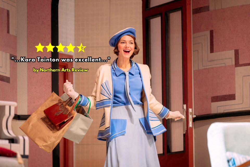 A woman in a blue beret and a 1920s style dress with cardigan smiles as she walks through a door in The Constant Wife